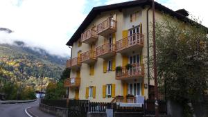 un edificio amarillo con balcones al lado de una carretera en Appartamenti hotel ortles en Cogolo