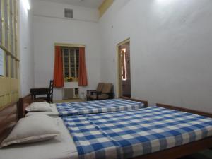 two beds in a bedroom with a blue and white checkered blanket at YWCA GALLWAY GUEST HOUSE in Kolkata
