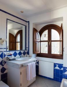 baño azul y blanco con lavabo y espejo en Hotel Tugasa Castillo de Castellar en Castellar de la Frontera