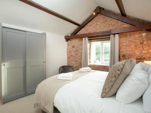 a bedroom with a large bed and a brick wall at The Cow Shack in Cadeleigh