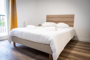 1 dormitorio con 1 cama grande con sábanas y almohadas blancas en Superbe T2 centre ville dernier étage avec balcon, en Valence