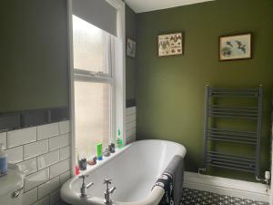 uma casa de banho verde com uma banheira e uma janela em Dracula Rooms em Whitby