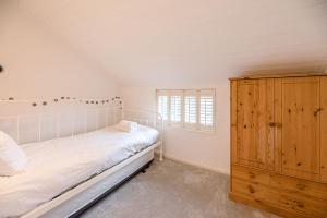 Schlafzimmer mit einem weißen Bett und einem Holzschrank in der Unterkunft Jenny Rose Cottage Wickham Market Air Manage in Woodbridge