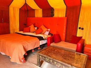 a bedroom with a bed and a couch and a chair at Your Family Camp in Merzouga