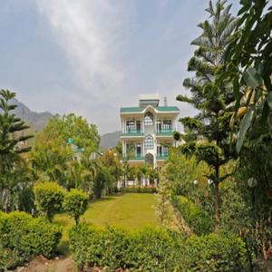 une grande maison avec une grande pelouse devant elle dans l'établissement Panambi Tapovan Resort, à Rishikesh
