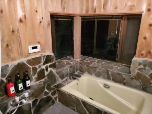 Oak Villa Nasu 抜群のプライベート空間 100インチ映像 轟音サウンド 人工芝デッキ في ناسو: حمام بحائط حجري وحوض استحمام +39 صورة