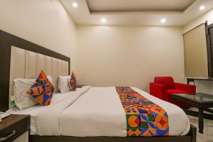 a bedroom with a bed and a red chair at FabHotel AGK in Haridwār