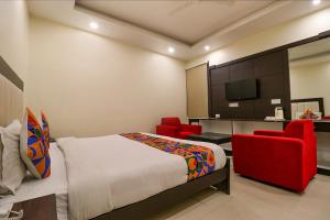 a bedroom with a bed and two red chairs at FabHotel AGK in Haridwār