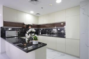 een keuken met witte kasten en een zwart aanrecht bij JBR The Walk Shams 4 - Fully Upgraded Sea view Lux 2 bedroom By Gardenia Holiday in Dubai