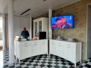Un homme debout dans une cuisine avec une télévision murale dans l'établissement Alimunera, à CastellʼUmberto