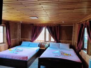 two beds in a train room with windows at Sunshine Hotel Kampot in Kampot