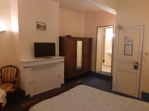 una habitación con TV en una cómoda y una puerta en Le Grand Cerf, en Nonancourt