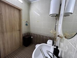 y baño con aseo, lavabo y espejo. en Квартира в центре Костаная, en Kostanái