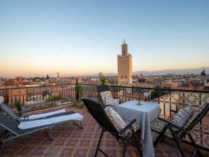 a balcony with a table and chairs and a clock tower at Dar Ben Saleh in Marrakesh