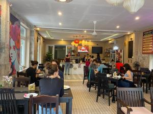 un grupo de personas sentadas en mesas en un restaurante en Golden Bell Backpacker Hotel & Pool Bar, en Hoi An
