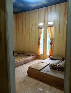 dwa łóżka w pokoju z dwoma oknami w obiekcie Faviliun haikal w mieście Cisarua