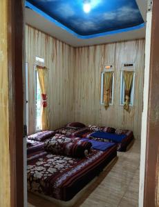 2 łóżka w pokoju z niebieskim sufitem w obiekcie Faviliun haikal w mieście Cisarua