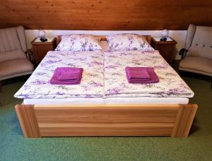 a bed with two purple pillows on it with two chairs at Chalupa pod strání in Telecí