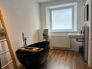 La salle de bains est pourvue d'une baignoire noire et d'un lavabo. dans l'établissement Schöne, sonnige Parterrewohung 3 Zi. mit Garten, à Poschiavo