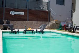 a pool with chairs and a table in the water at Apart Porto del Sol by CPH in Villa Carlos Paz