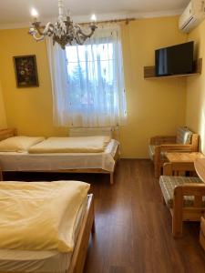 a room with three beds and a tv and a window at Barokk Hotel in Hegyeshalom