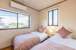 two beds in a room with a window at Sayuragi Villa 白浜 in Shirahama