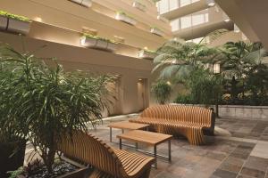 a lobby with tables and benches and palm trees at Hyatt Regency Orlando International Airport Hotel in Orlando
