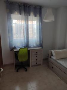 a bedroom with a desk and a bed and a green chair at Apartamento en primera línea de playa con vistas in Cabanes +15 photos