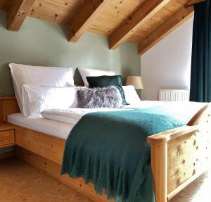 1 dormitorio con cama de madera y almohadas blancas en Das Bergquartier - Ferienwohnung Krottenkopf, en Oberau