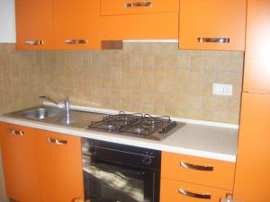 an orange kitchen with a stove and a sink at Appartamento Giacomo in Cavo