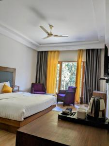 a hotel room with a bed and purple chairs at The 9 Oaks by BOP group of Stay and Cafe in Mussoorie