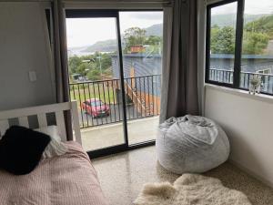 Schlafzimmer mit einem Bett und einem großen Fenster mit Aussicht in der Unterkunft Commanding Harbour views exquisite sunset vista in Dunedin