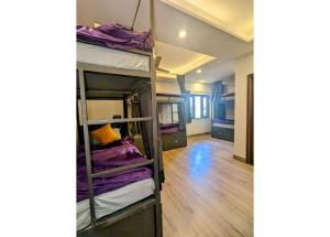 a room with three bunk beds with purple blankets at The 9 Oaks by BOP group of Stay and Cafe in Mussoorie