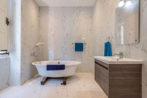 a white bathroom with a tub and a sink at Spacious 4-Bedrooms Townhouse in Tas-Sliema in Sliema