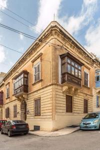 an old building with windows and cars parked in front of it at Spacious 4-Bedrooms Townhouse in Tas-Sliema in Sliema