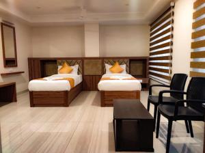 a hotel room with two beds and a table and chairs at RR Mount Elite Suites in Chennai