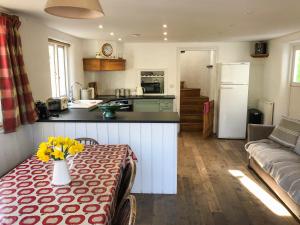 una cocina y una sala de estar con una mesa con flores amarillas. en Shute Cottage, en Manorbier