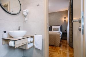La salle de bains est pourvue d'un lavabo, d'un miroir et d'un lit. dans l'établissement Apartments Hana City Center, à Livno