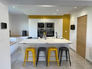 uma cozinha com uma grande ilha com três bancos amarelos em Villa des églantiers baie de somme em Cayeux-sur-Mer