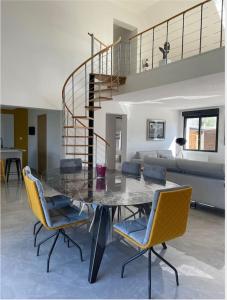 a dining room table with chairs and a spiral staircase at Villa des églantiers baie de somme in Cayeux-sur-Mer