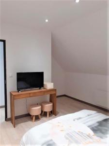 een slaapkamer met een bureau, een televisie en een bed bij Villa des églantiers baie de somme in Cayeux-sur-Mer