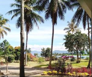 uma vista para um parque com palmeiras e flores em Batajaya Cottage em Panjaitan
