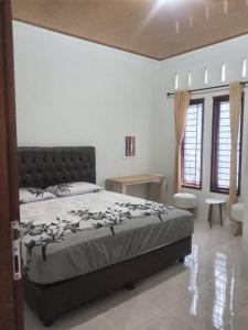 a bedroom with a bed and a table and windows at Batajaya Cottage in Panjaitan