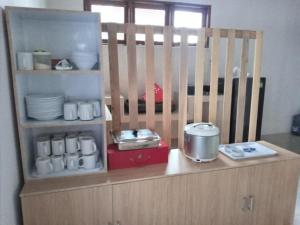 eine Küche mit einem Schrank mit Geschirr und Geräten in der Unterkunft Batajaya Cottage in Panjaitan