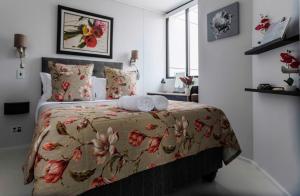 1 dormitorio con 1 cama con colcha de flores en Flamingo Sea Point Sea View Luxury Best Position 1 Bedroom Apartment Queen Size Bed & Inverter For TV, en Ciudad del Cabo