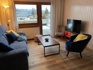 uma sala de estar com dois sofás e uma televisão em Au village de Nax, ravissant 2 pièces et demi avec terrasse em Nax