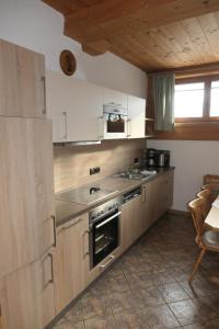eine Küche mit weißen Schränken, einer Spüle und einem Herd in der Unterkunft Ferienwohnung Schaffenrath in Kaltenbach