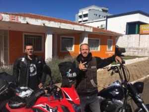 dos hombres están parados al lado de una motocicleta roja en Hotel Pousaria en Guarapuava