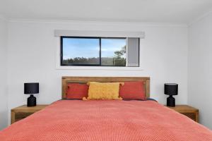 a bedroom with a bed with a red comforter and a window at High View on the Hill in St Helens