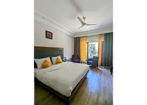 a bedroom with a bed and a ceiling fan at The 9 Oaks by BOP group of Stay and Cafe in Mussoorie
